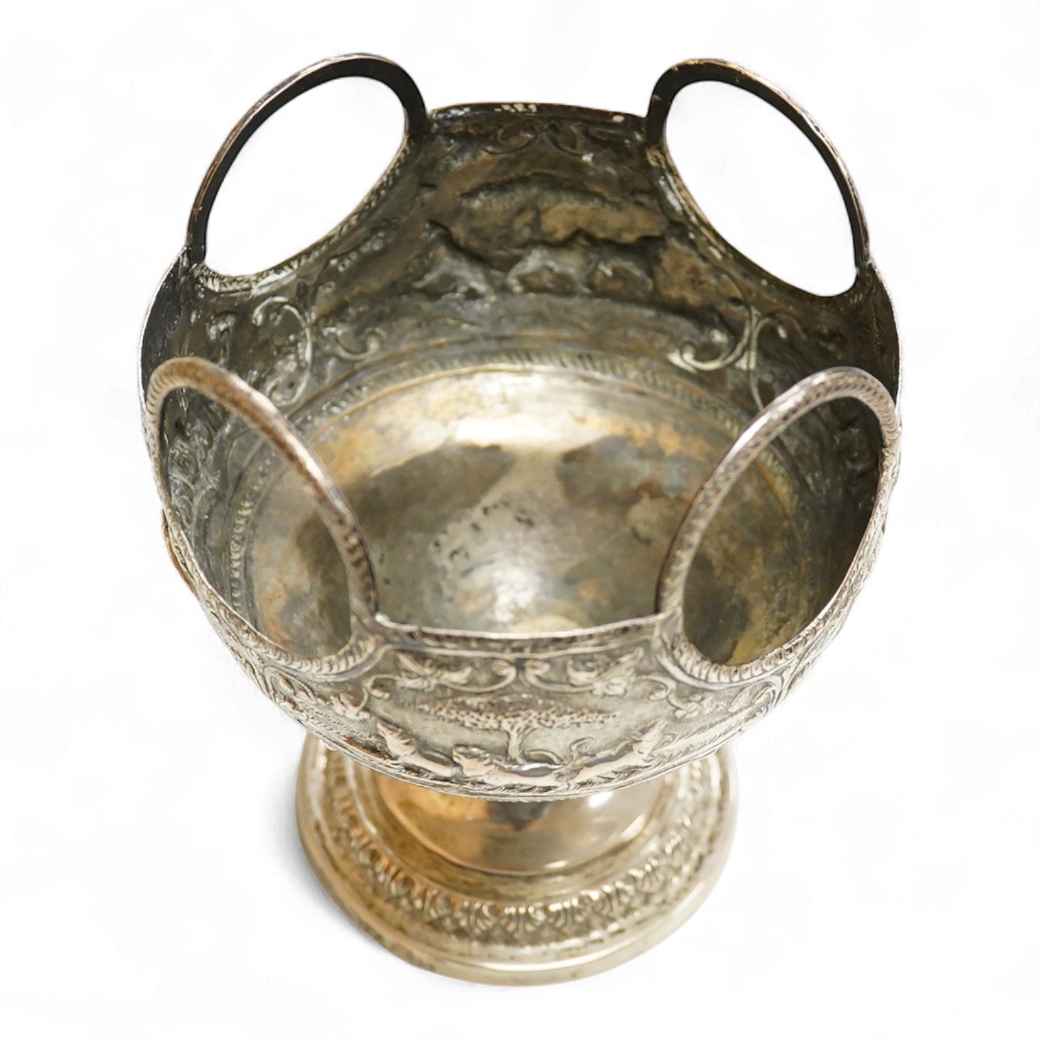 A late 19th/early 20th century Indian white metal pedestal bowl, with unusual ring handle border, embossed with continuous scene of wild animals, diameter 12.3cm, 6.3oz.